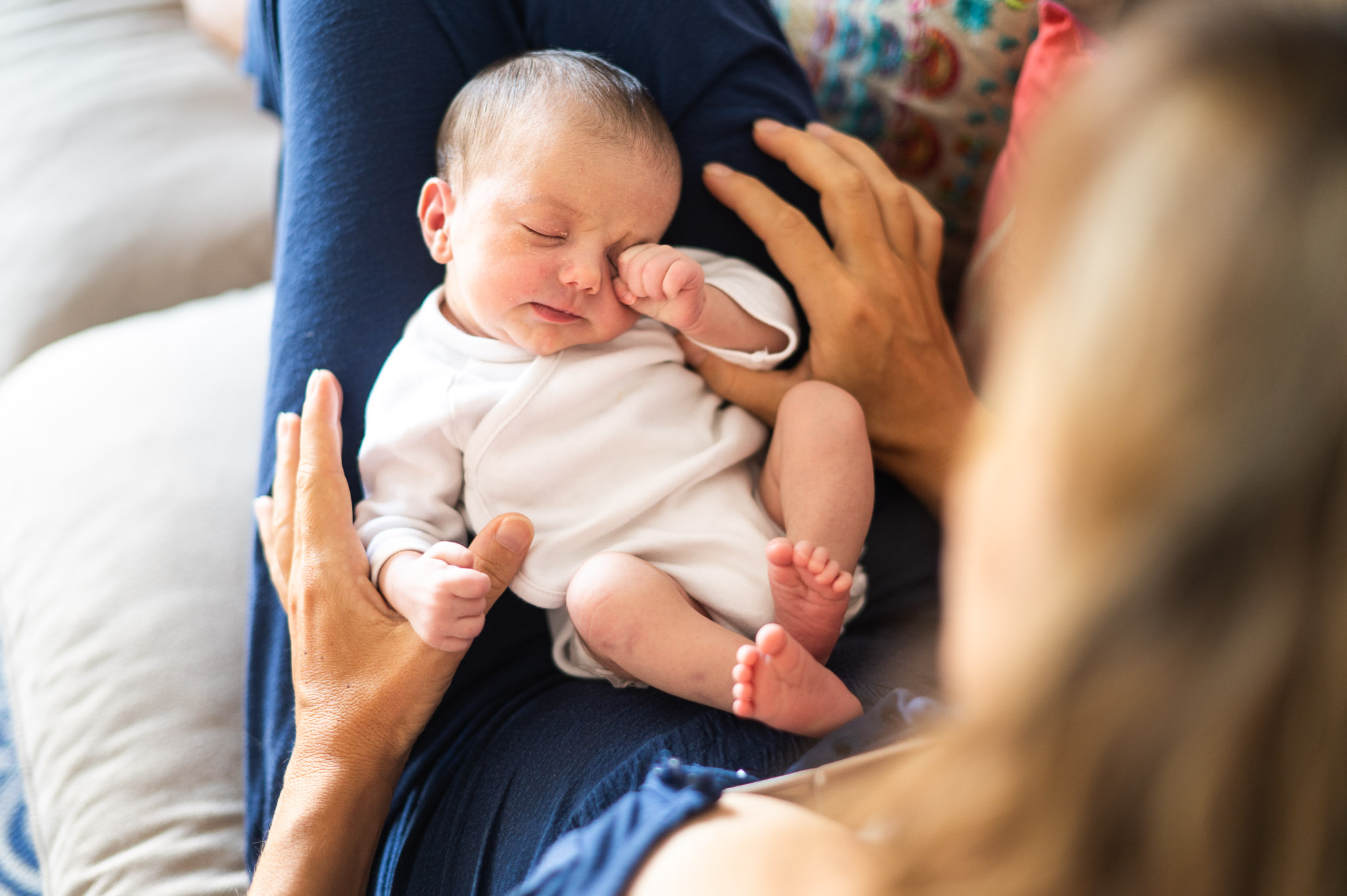 un bebe se frotte les yeux lors d'une séance photo à domicile