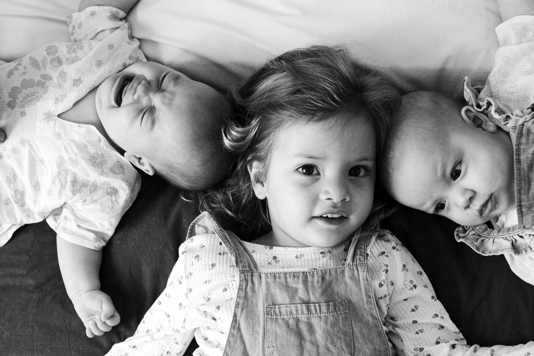 trois petites filles sont sur un lit