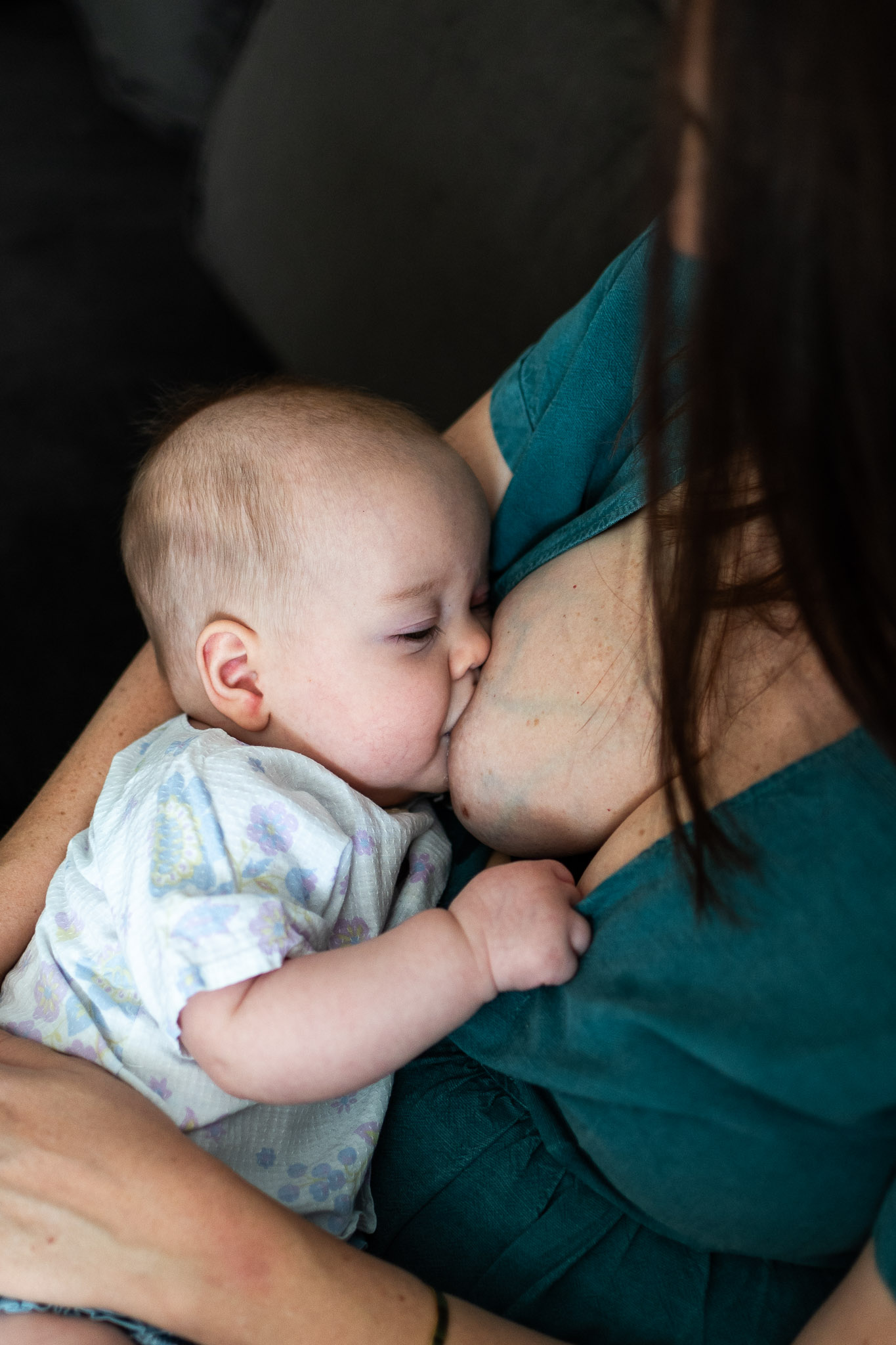 un bébé tètete sa maman lors d'une séance photo à domicile